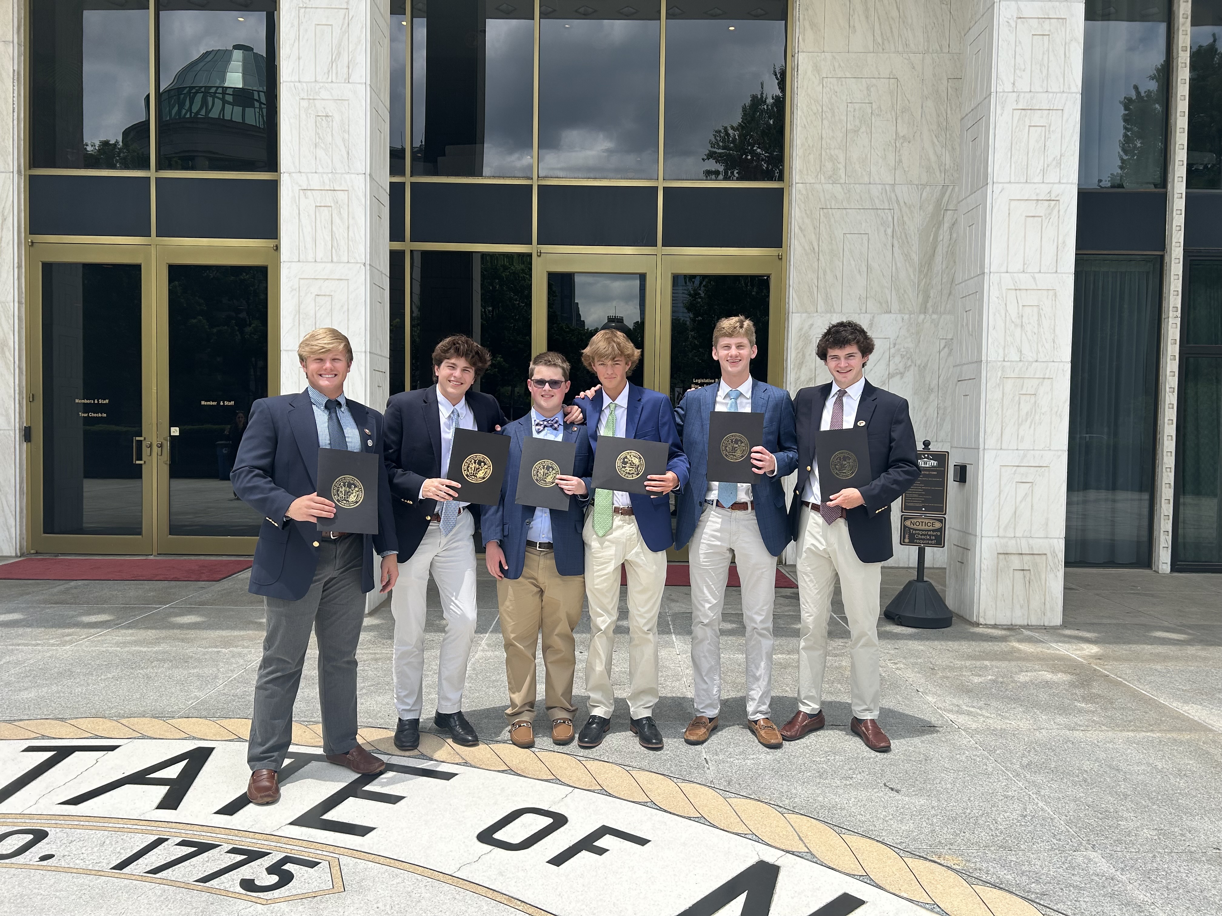 6 Pages stand holding folders in front of the legislative building